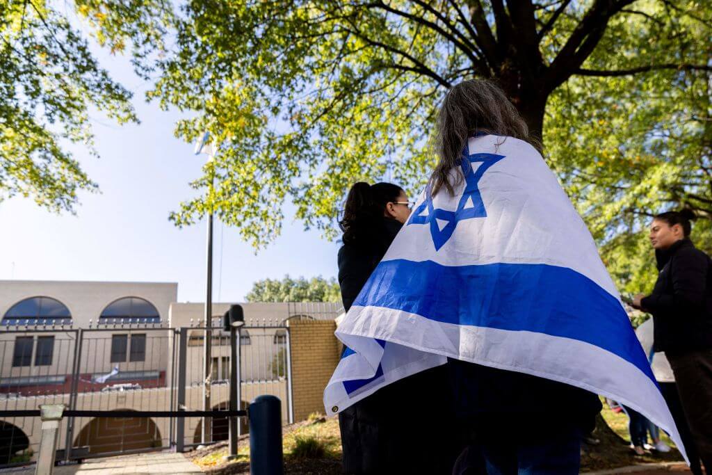 A supporter of Israel draped in an Israeli flag in front of the Israeli Embassy in Washington, D.C.