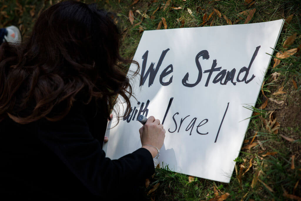 A woman writes "We Stand with Israel" on a poster outside of the Israeli Embassy on Oct. 8, 2023.