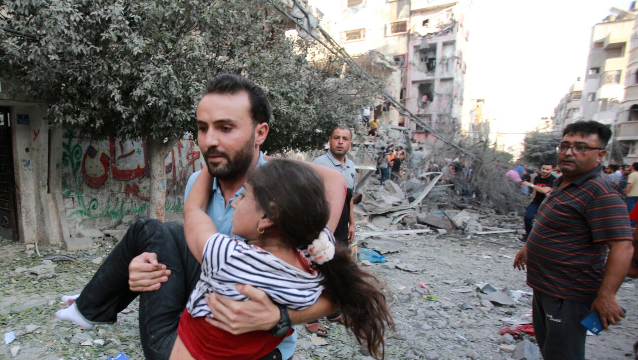 A man evacuates a wounded girl from the site of an Israeli strike on Gaza City on Tuesday. As Israeli airstrikes in response to the Hamas attack on Saturday mount, leading Palestinian advocacy groups are calling on lawmakers to address the "root cause" of the violence — which they argue is the Israeli occupation — rather than relying on a military response.