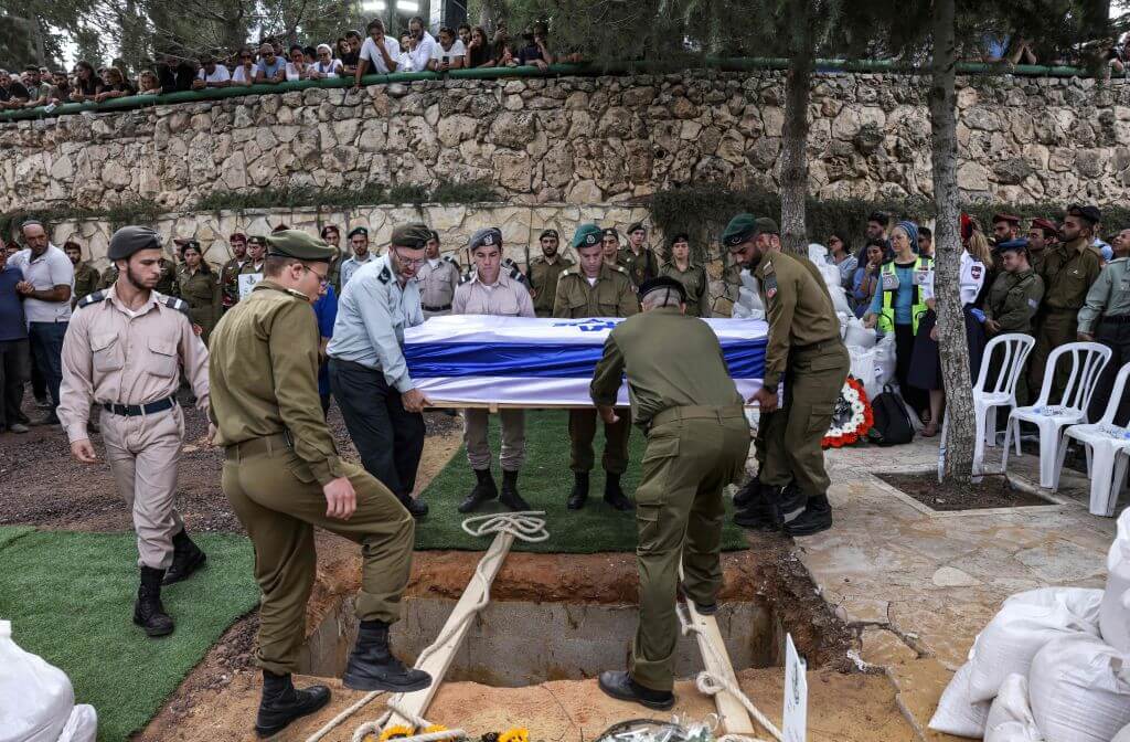 Soldiers lower the casket of French-Israeli soldier Eli Valentin Ghenassia, who was killed in combat at Kibbutz Beeri during an infiltration by Hamas militans, during his funeral in the Mount Herzl cemetery in Jerusalem on October 12, 2023.