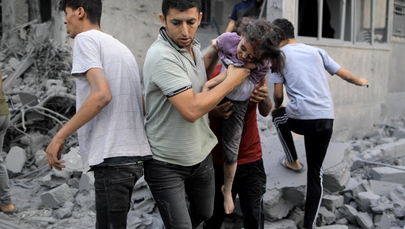 A Palestinian man rescues a girl from the rubble of a building following an Israeli strike in Khan Yunis in the southern Gaza Strip. (YASSER QUDIH/AFP via Getty Images)