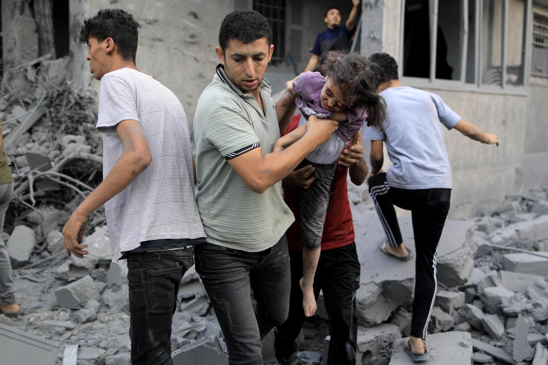 A Palestinian man rescues a girl from the rubble of a building following an Israeli strike in Khan Yunis in the southern Gaza Strip. (YASSER QUDIH/AFP via Getty Images)