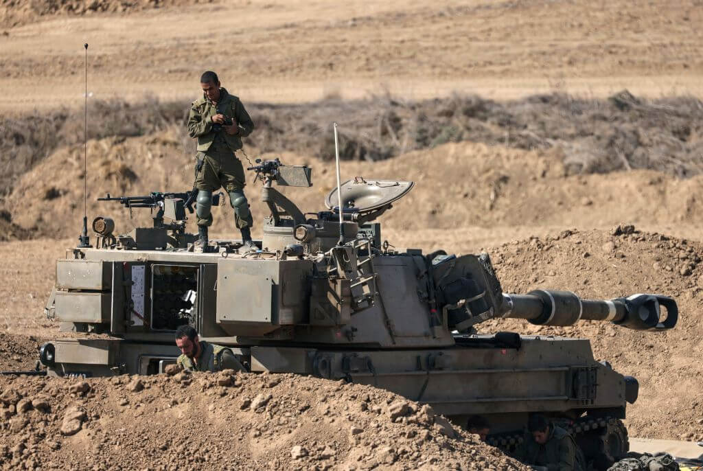 An Israeli soldier stands on an armoured vehicle stationed close to the border with the Gaza Strip on October 15, 2023.