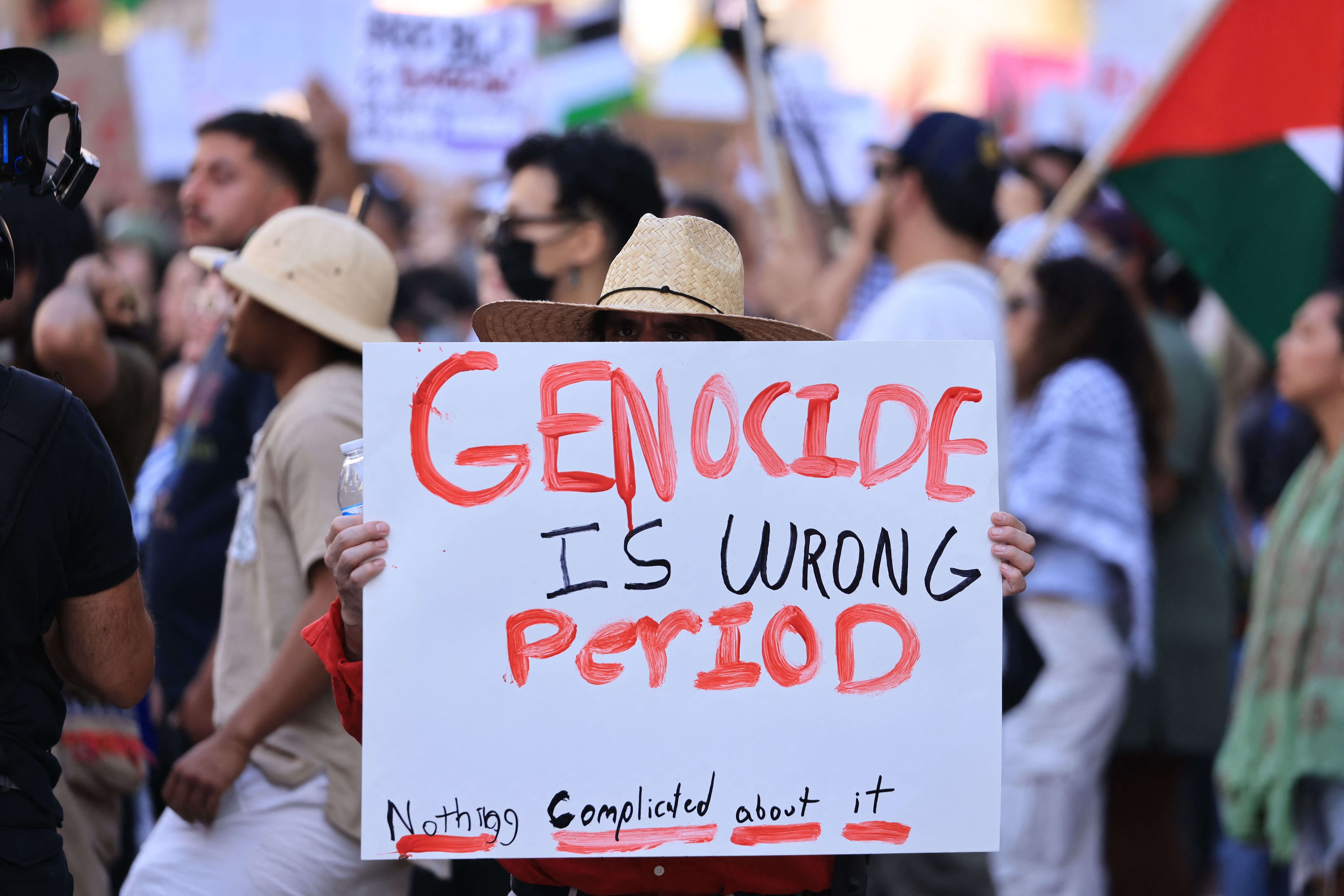 A protestor holds a "Genocide is Wrong, Period" sign at a rally in Los Angeles.