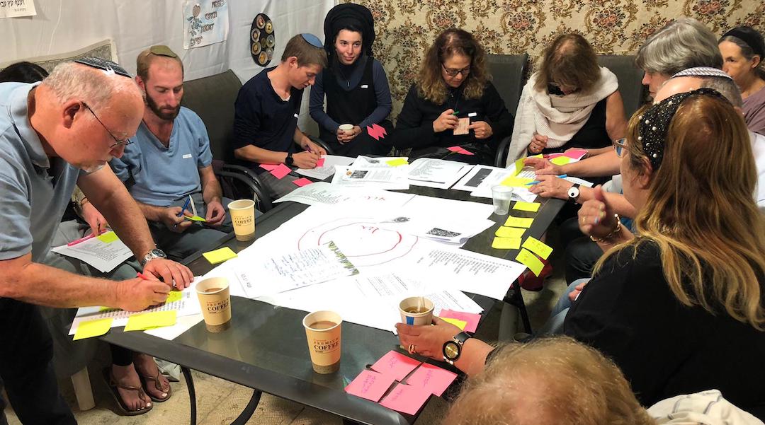 Participants complete an exercise during a dialogue session at an Israeli sukkah as part of the SOS Home project. (Courtesy of SOS Home)