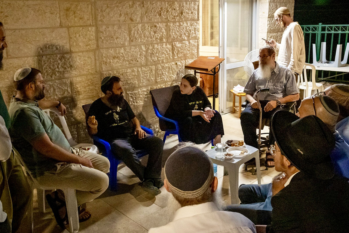 Residents of Mitzpe Yericho gather in the home of Rabbi Achiya Eliyahu (seated, in the black T-shirt) and Idit Eliyahu, who are sitting shiva following the death of their 19 year-old son, Ariel. (Laura Ben-David)