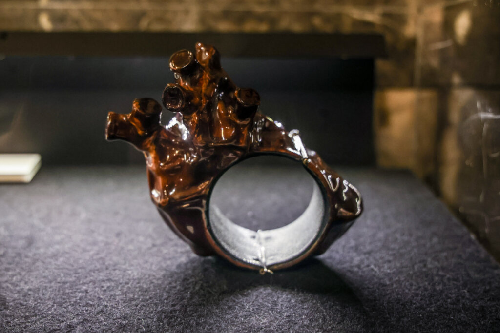 A shiny heart-like sculpture with a wide hole in the center making it a bracelet.