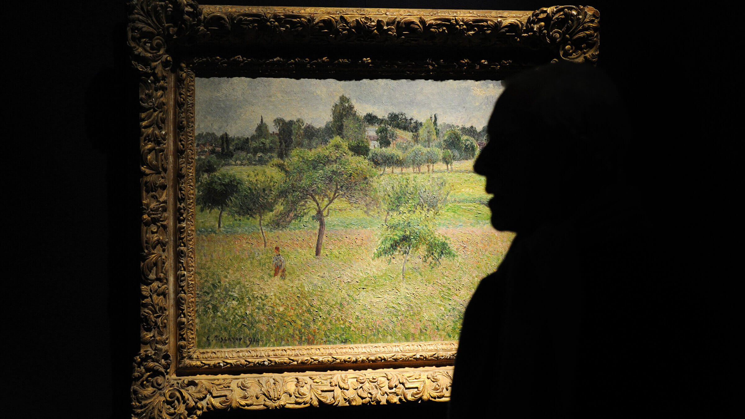A visitor views an 1894 painting by Camille Pissarro.