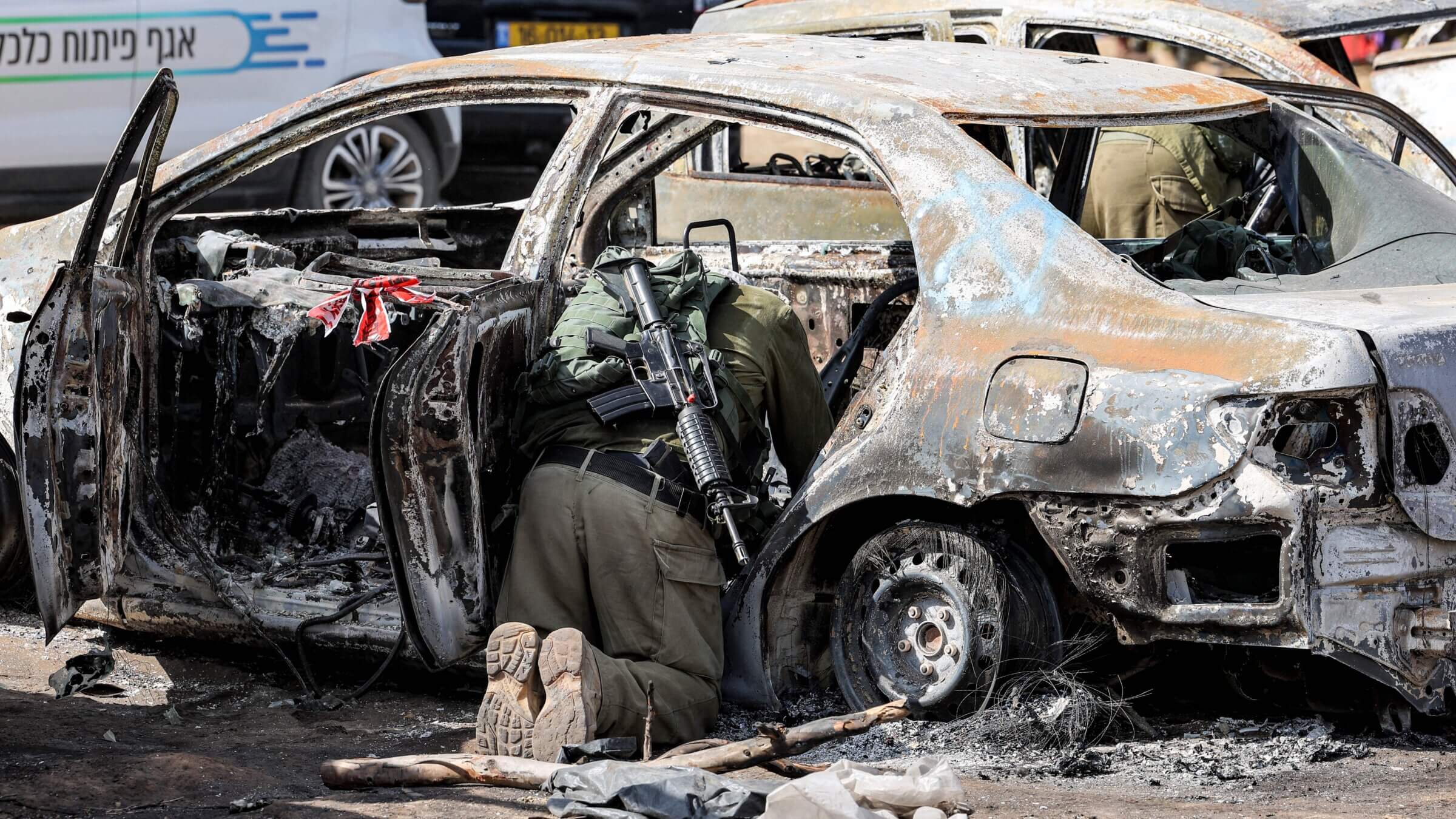An Israeli army soldier searches and collects forensic evidence through a torched vehicle at the site of the Oct. 7 attack on the Supernova desert music festival.