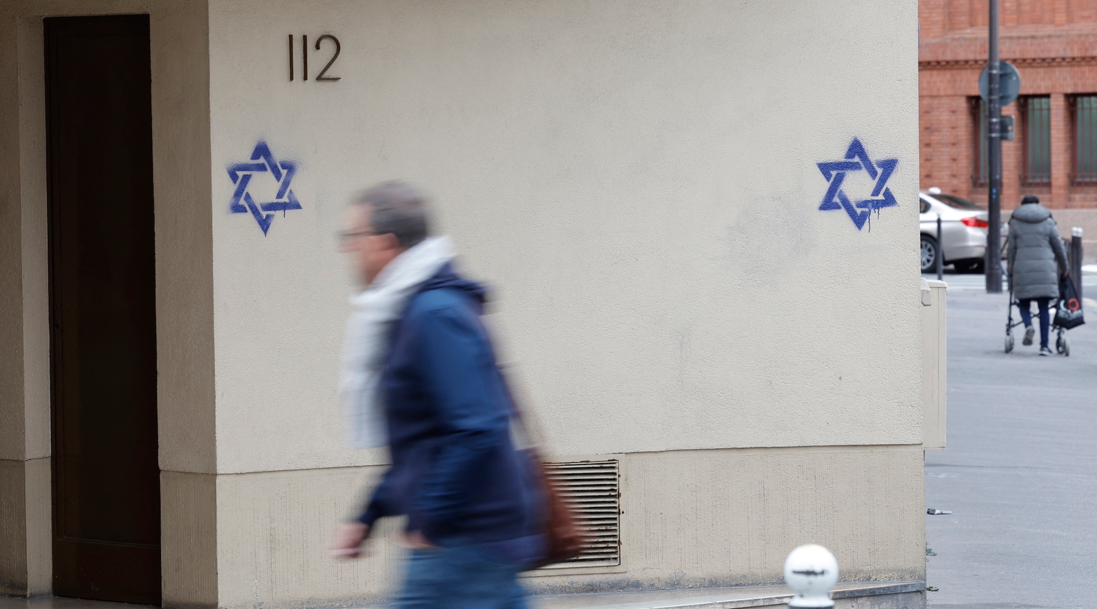 A man walks along a building whose facade is covered with Stars of David in the Alesia district of Paris, Oct. 31, 2023. (Geoffroy van der Hasselt/AFP via Getty Images)