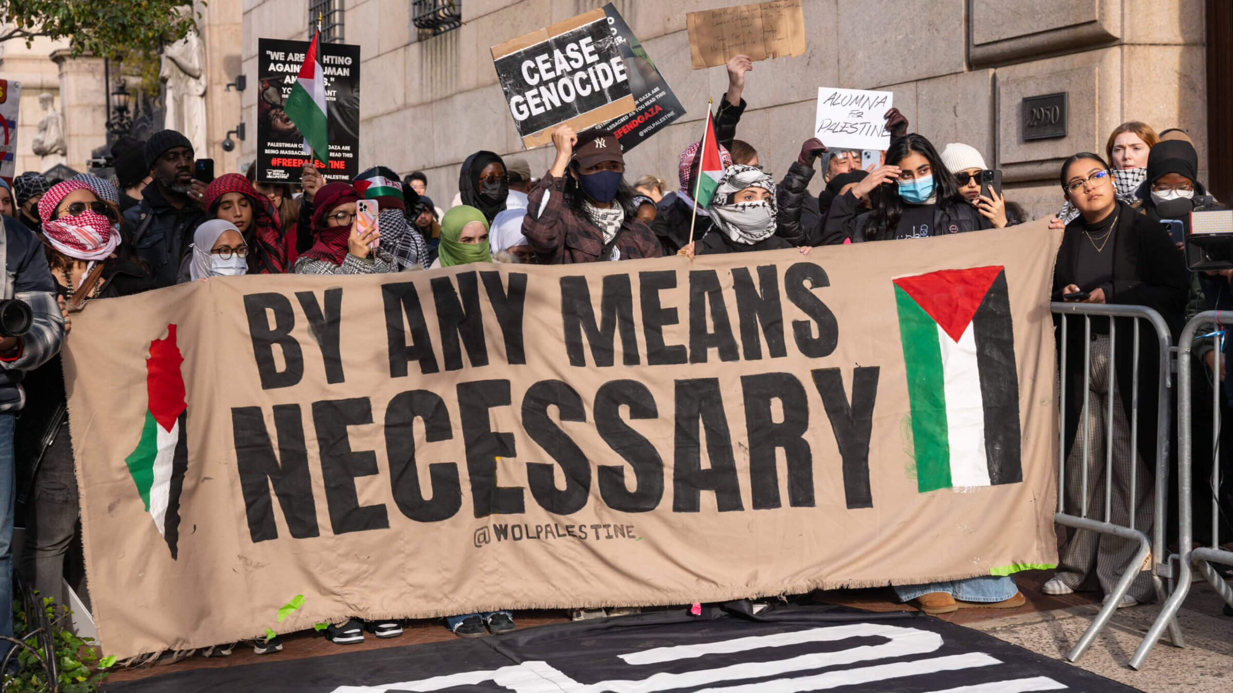 Students participate in a protest in support of Palestine outside of the Columbia University campus on Nov. 15. A large banner reads, "by any means necessary," with an image of the Palestinian flag