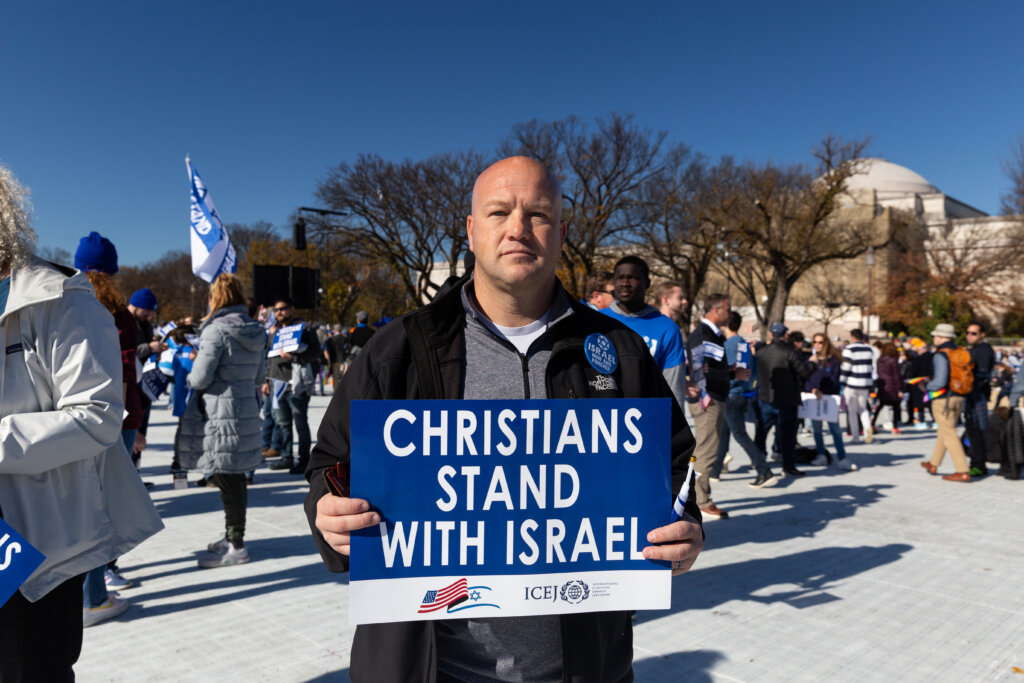 A man holds a sign that reads "Christians stand with Israel"