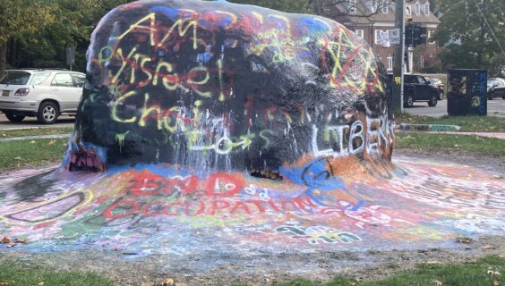 The Rock, a landmark by the University of Michigan, covered in graffiti with slogans about the war. Jewish stars and the phrase "Am Yisrael Chai" were painted over in red.