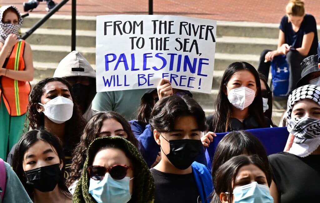 A participant holds a "From the River to the Sea" poster as students gather during a "Walkout to fight Genocide and Free Palestine" at the University of California, Los Angeles. 