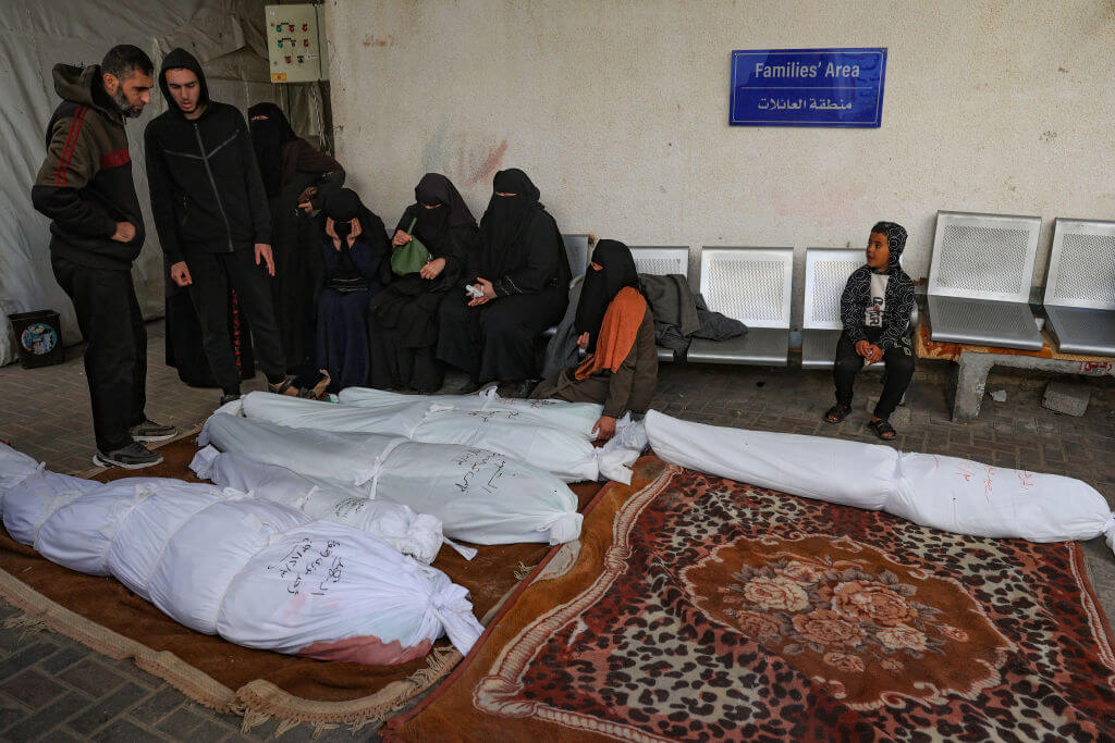 People sit beside the shrouded corpses of relatives killed in Israeli bombing on Rafah in the southern Gaza Strip, at the morgue of the al-Najjar hospital on Dec. 3. Israel carried out deadly bombardments in Gaza as international calls mounted for greater protection of civilians and the renewal of an expired truce with Palestinian militant group Hamas. 