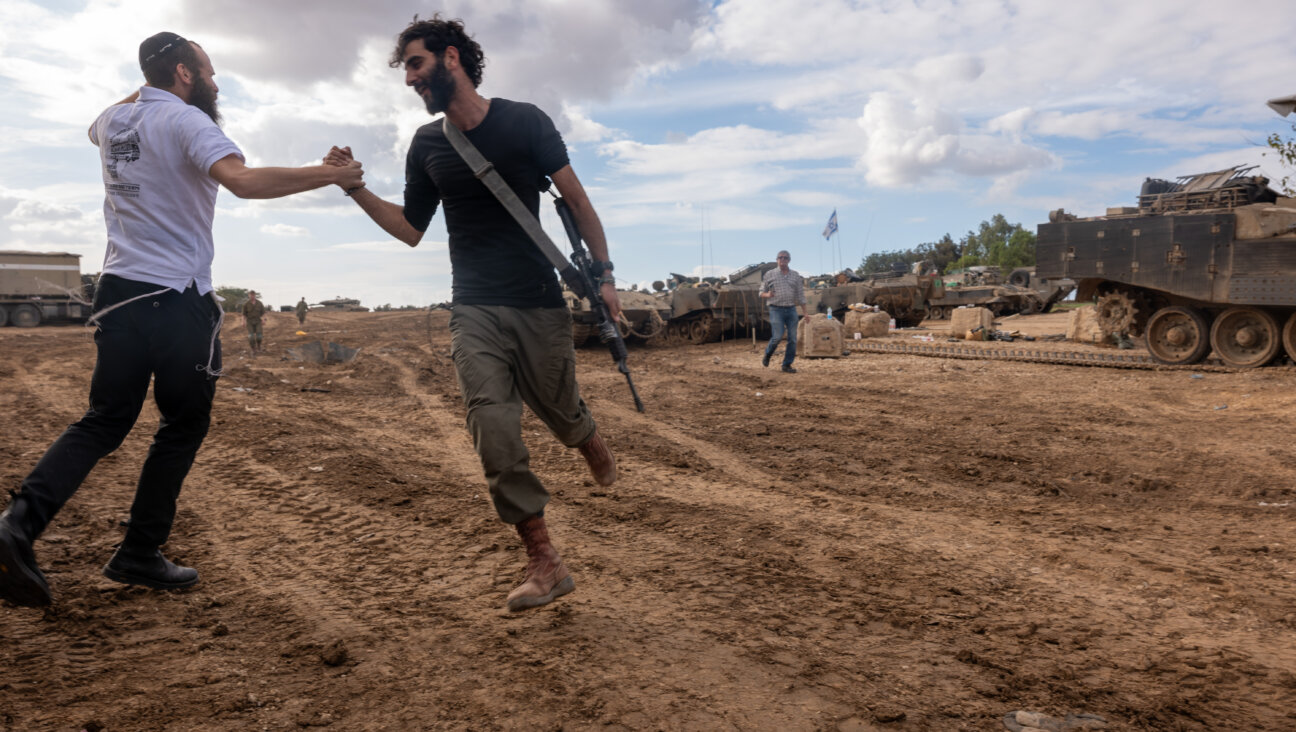 Members of the Israeli Defense Forces (IDF) dance with a member of the Haredi Orthodox community at a staging area near the border of Gaza on Nov. 28, 2023 outside of the city of Sderot, Israel