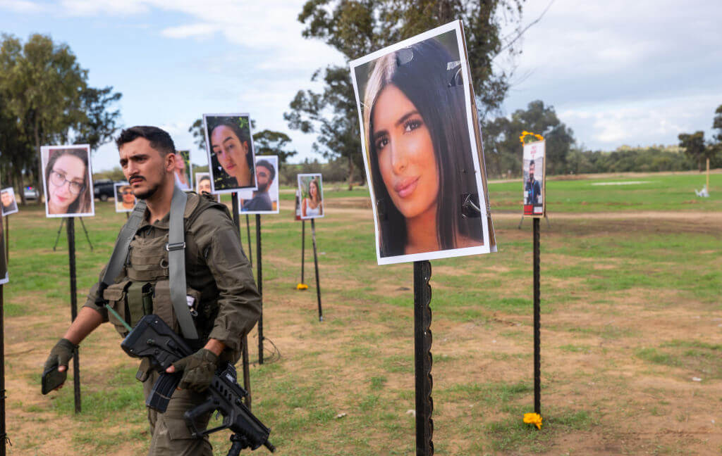 An Israeli soldier walks among pictures of victims of the Nova music festival at the site of the October 7th massacre near Kibbutz Re'im and the border with Gaza.