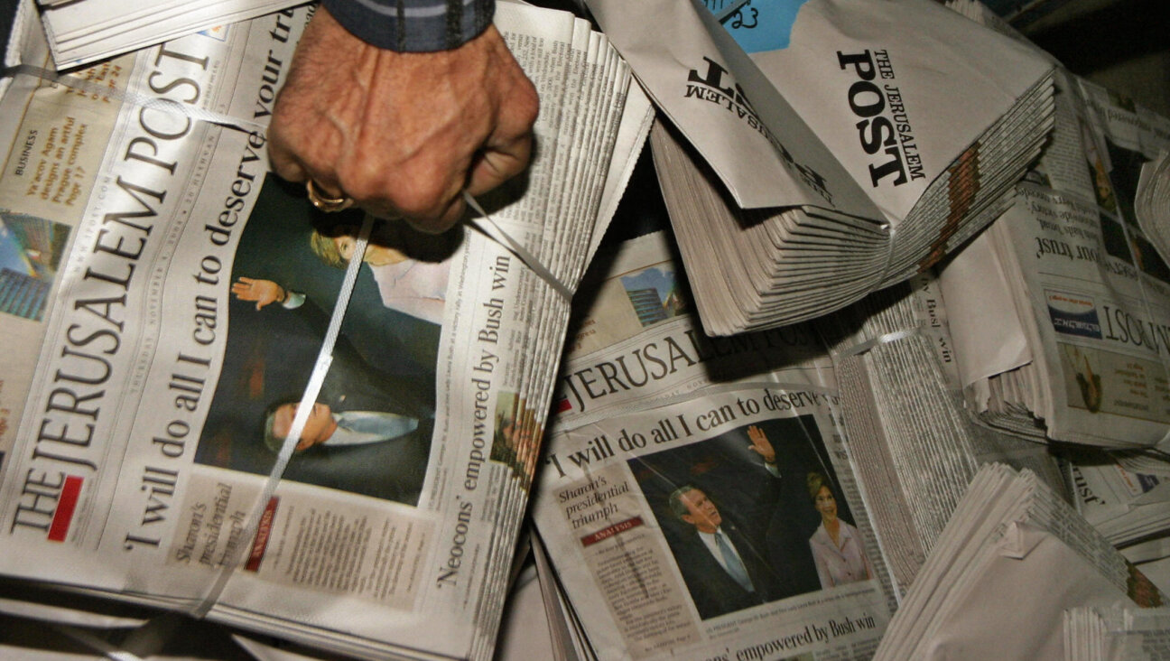 A worker for the English-language Israeli newspaper Jerusalem Post grabs a pile of papers in 2004, the year that Israeli businessman Eli Azur purchased the newspaper. Current and former employees say the newspaper, which parted ways with its top editor this week, has faced a variety of problems in the years since Azur's acquisition.
