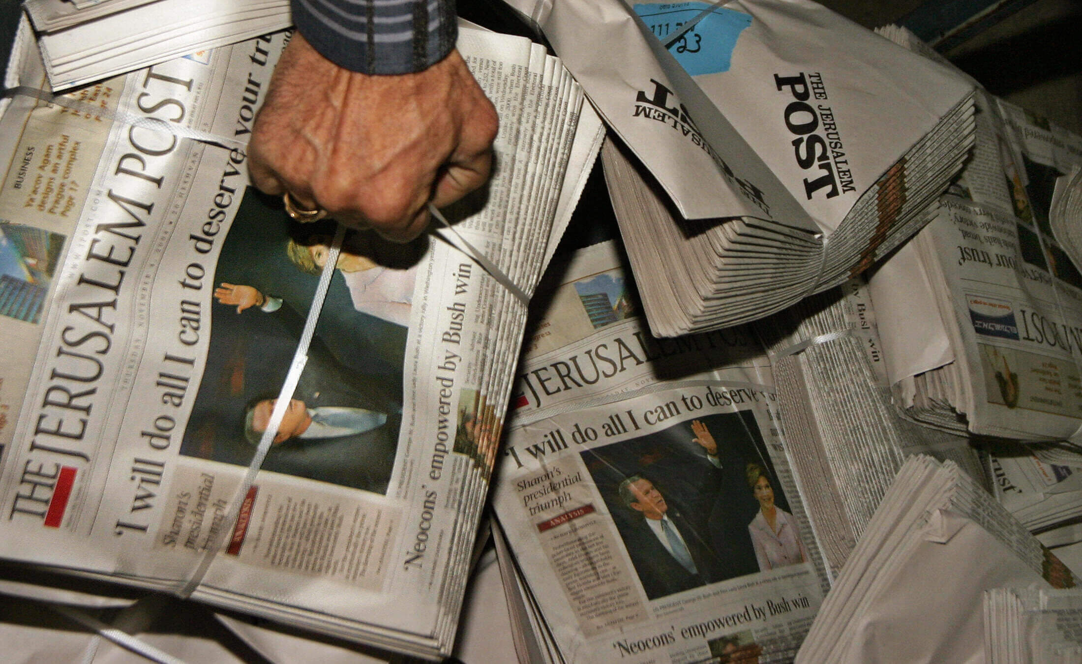 A worker for the English-language Israeli newspaper Jerusalem Post grabs a pile of papers in 2004, the year that Israeli businessman Eli Azur purchased the newspaper. Current and former employees say the newspaper, which parted ways with its top editor this week, has faced a variety of problems in the years since Azur's acquisition.