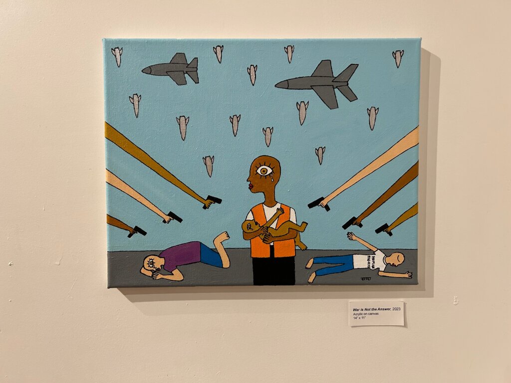 Painting of arms with guns pointing at a dark-skinned person holding a baby and standing up. Two people cower on the ground, one with a shirt that says "human rights" on it. Airplanes fly in the sky and bombs fill the sky.