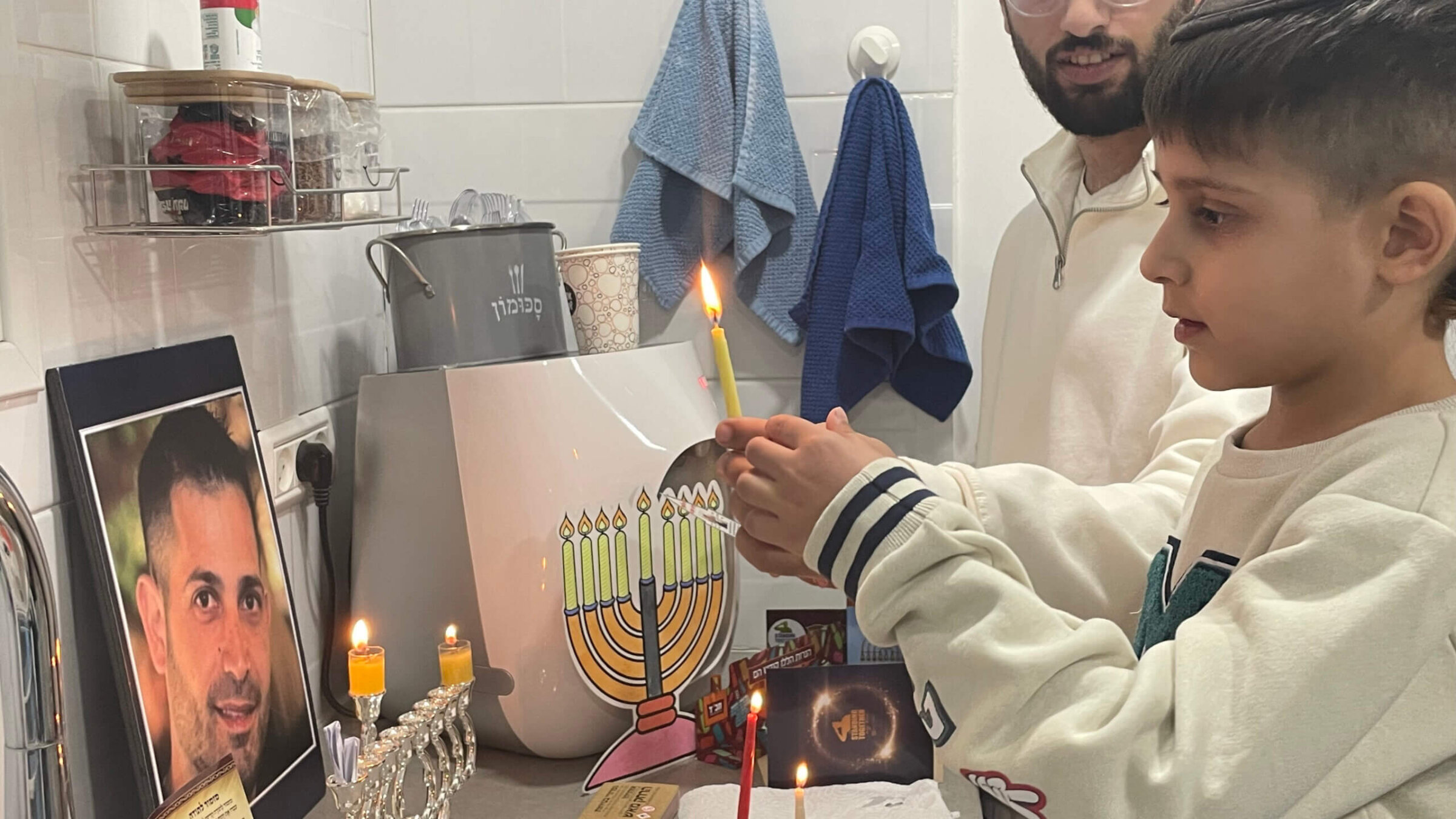 Ofek Baruch, 5, lights the first candle while looking at a photo of his father, Uriel, one of more than 100 Israeli hostages still held in captivity in the Gaza Strip.