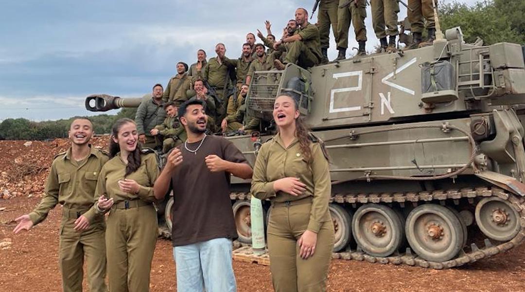 Yagel Oshri, whose song “Getting Over Depression” has become an unofficial anthem of Israel’s war with Hamas, poses with Israeli soldiers at an army base during a recent goodwill tour. (Courtesy Yagel Oshri)