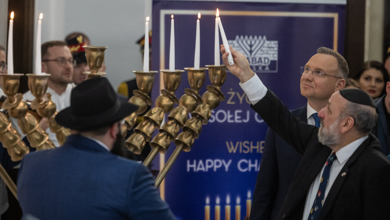 Polish President Andrzej Duda, <i>second from right</i>, looks on as Chief Rabbi of Poland Michael Schudrich, <i>right</i>, kindles the Hanukkah menorah in the Polish Parliament in Warsaw, on Dec. 14 — a day after far-right lawmaker Grzegorz Braun used a fire extinguisher to put out the candles.