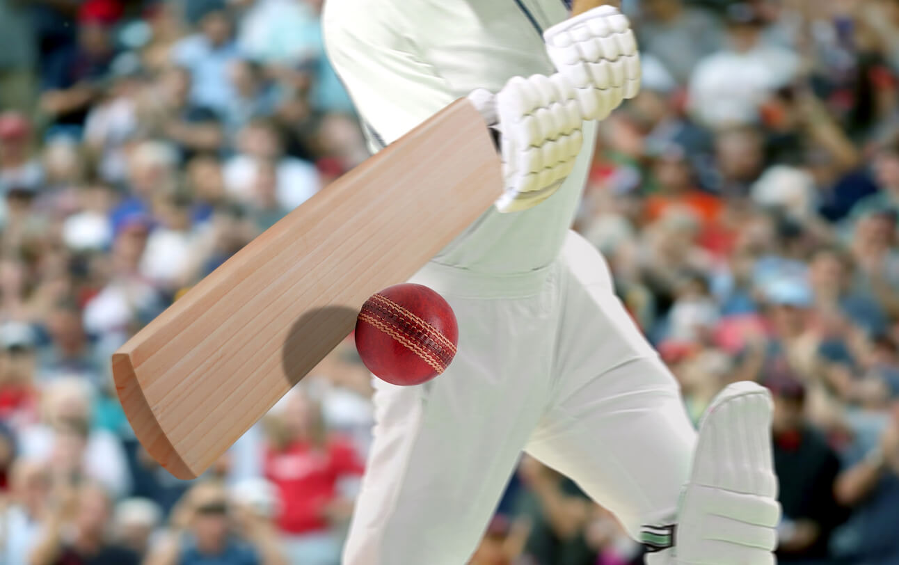 A cricket player hitting the ball in a stadium.