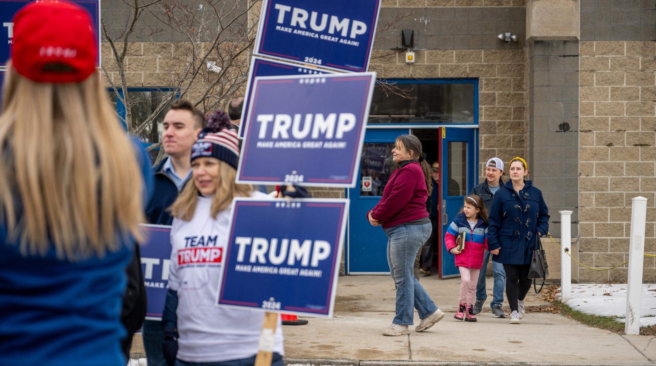 People exit a polling center at Londonderry High School as Trump supporters rally outside, in Londonderry, New Hampshire, Jan. 23, 2024. (Brandon Bell/Getty Images)