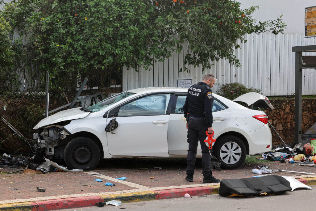 A member of Israeli police inspects a damaged car following a suspected ramming attack in the central town of Raanana, on January 15, 2024.