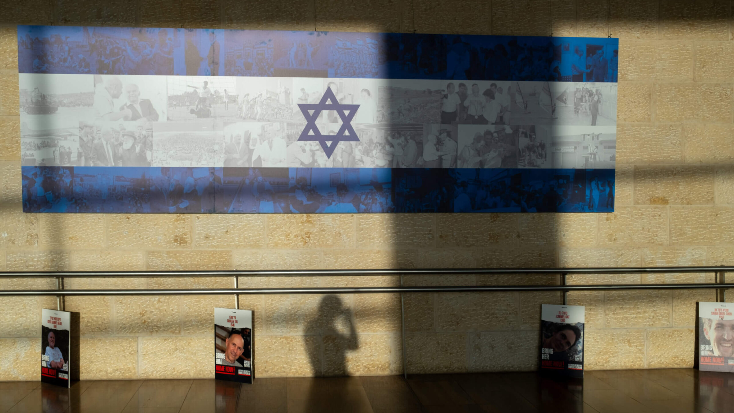 People walk past posters of hostages displayed before entering the departures hall in the Ben Gurion Airport on Dec. 25, 2023.