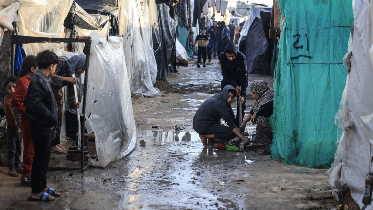 Displaced Palestinians in Gaza gather amid tents flooded by heavy rain, at a makeshift camp set up by people who fled the ongoing battles between Israel and Hamas.