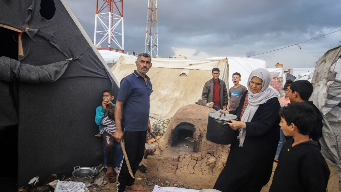 Displaced Palestinians  prepare food beside temporary shelters at a camp operated by the United Nations Relief and Works Agency in Khan Younis, Gaza, on Nov. 19, 2023