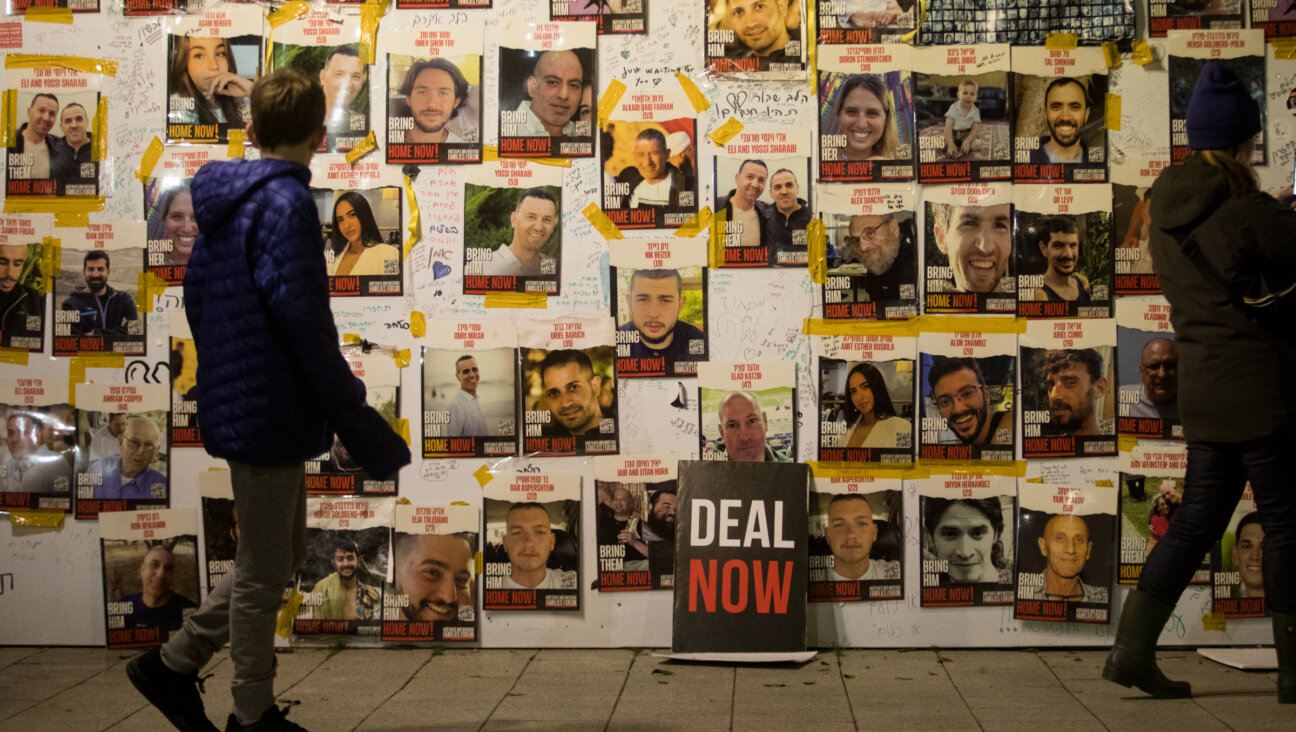 People walk by a wall with photos of hostages held in the Gaza Strip by Hamas during a rally calling for release of all hostages on Jan. 27 in Tel Aviv.