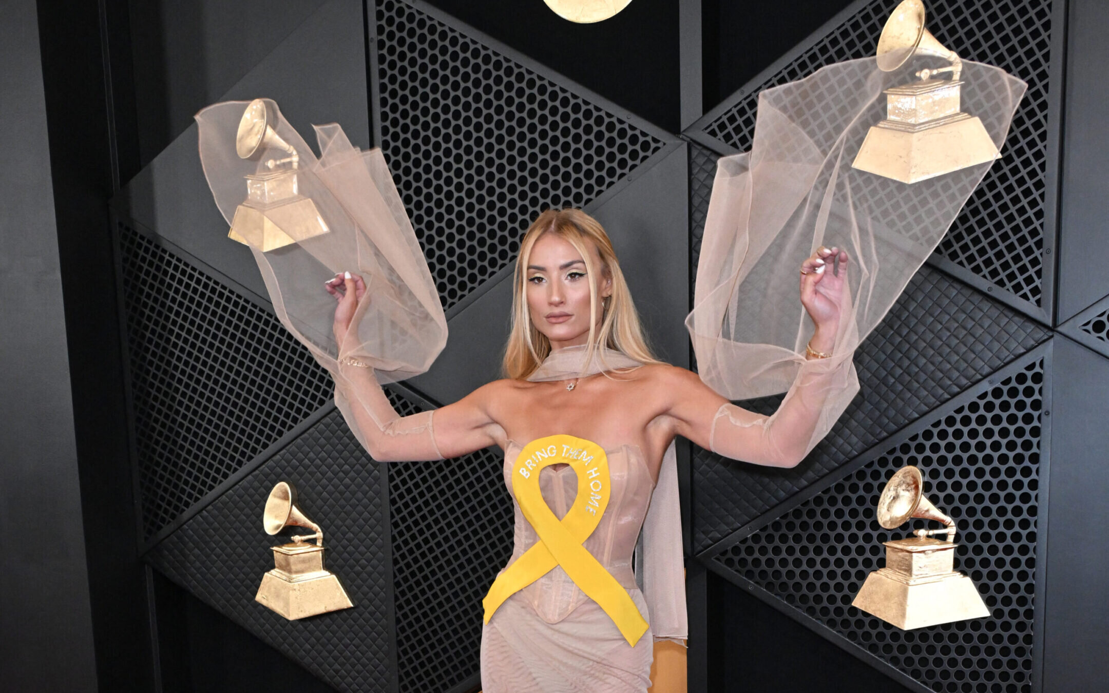 Singer and influencer Montana Tucker arrives for the 66th Annual Grammy Awards at the Crypto.com Arena in Los Angeles on February 4, 2024, wearing a dress with a yellow ribbon meant to call attention to the Israeli hostages in Gaza. (Photo by Robyn Beck/AFP via Getty Images)