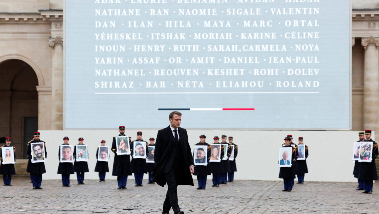 French President Emmanuel Macron walks in front of members of the French Republican Guard holding portraits of the 42 French and French-Israeli citizens killed in Israel on Oct. 7, 2023, during a ceremony to pay tribute to the French victims of the attack by Hamas, at the Invalides memorial complex in Paris, Feb. 7, 2024. (Gonzalo Fuentes/AFP via Getty Images)