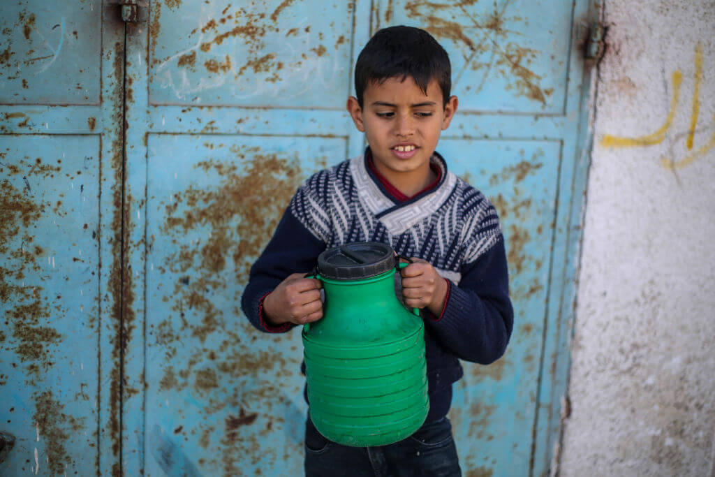 A Palestinian child collect water as people suffer water shortages due to the war on February 29, 2024 in Rafah, Gaza. 
