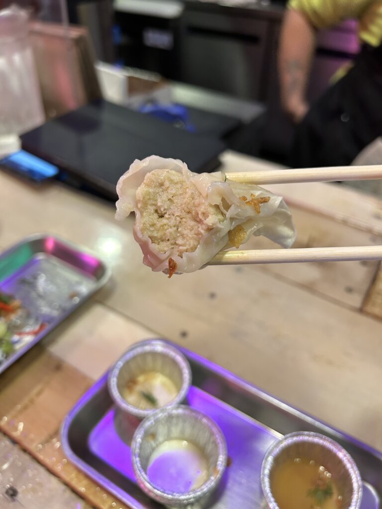 A cross section of a dumpling between chopsticks, filled with a dense matzo ball mixture.