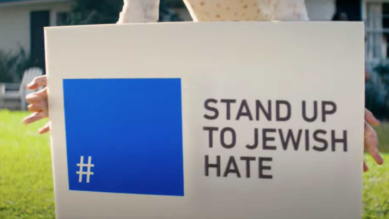 A woman places a lawn sign with the slogan "Stand Up To Jewish Hate" during a scene from a Super Bowl advertisement from the Foundation to Combat Antisemitism.