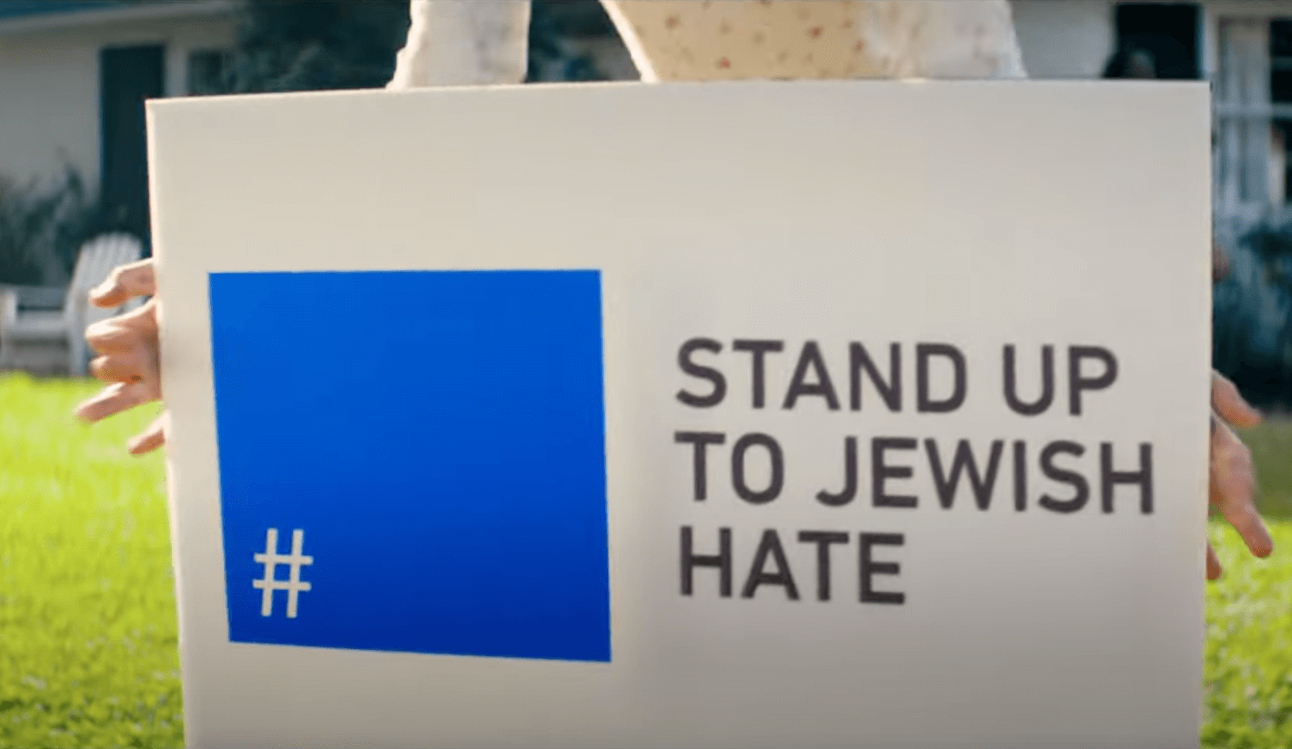 A woman places a lawn sign with the slogan "Stand Up To Jewish Hate" during a scene from a Super Bowl advertisement from the Foundation to Combat Antisemitism.