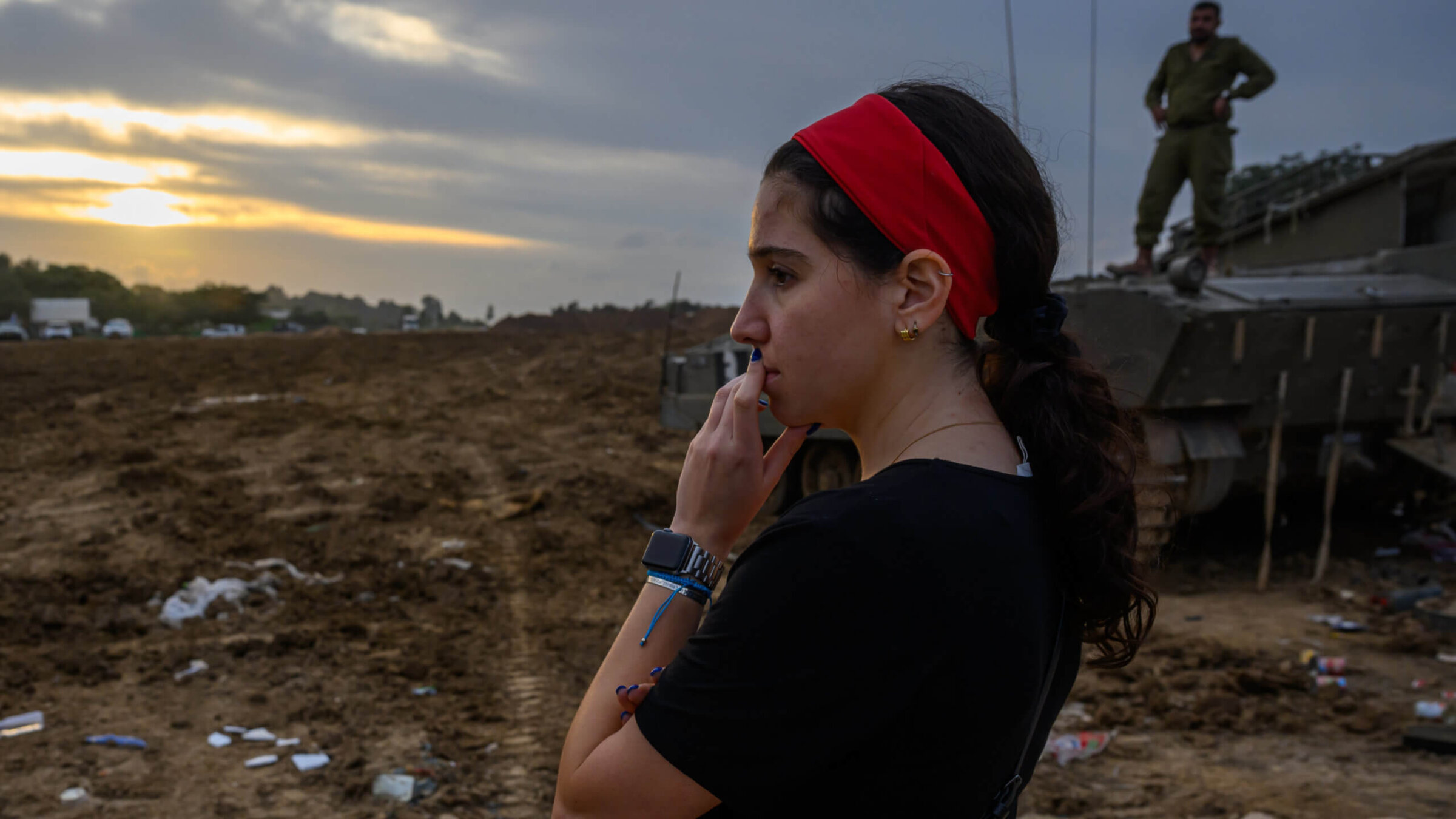 A woman watches as IDF forces arrive to a staging area in the Gaza Envelope for the first time since the Hamas attack,  Dec. 17,  in Southern Israel. 