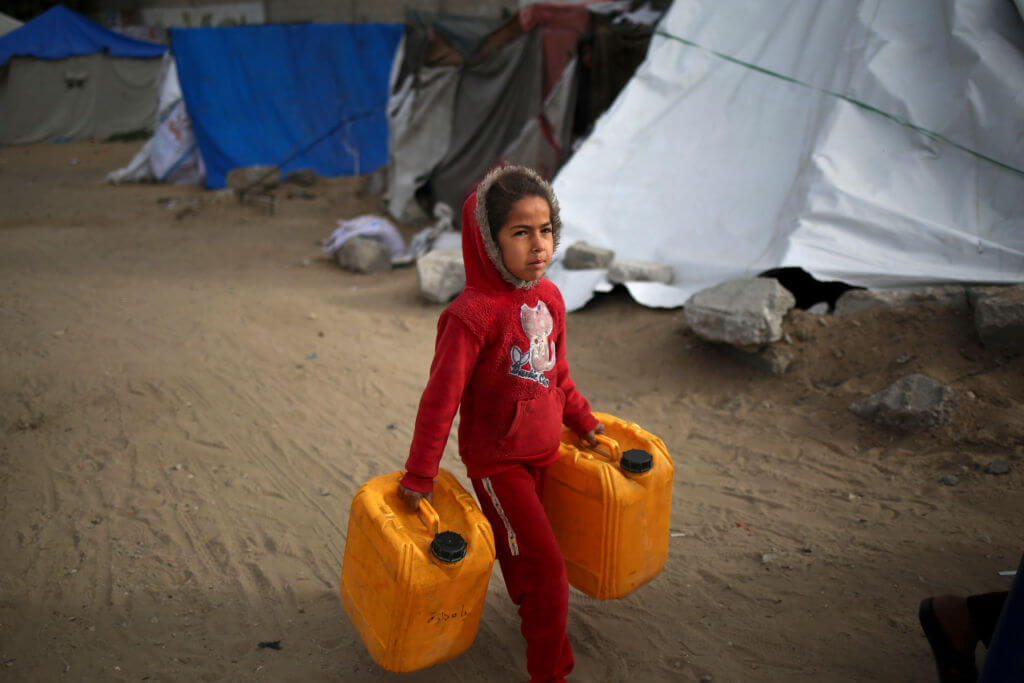 A Palestinian girl carries water containers along a street in Rafah in the southern Gaza Strip on March 3, 2024.