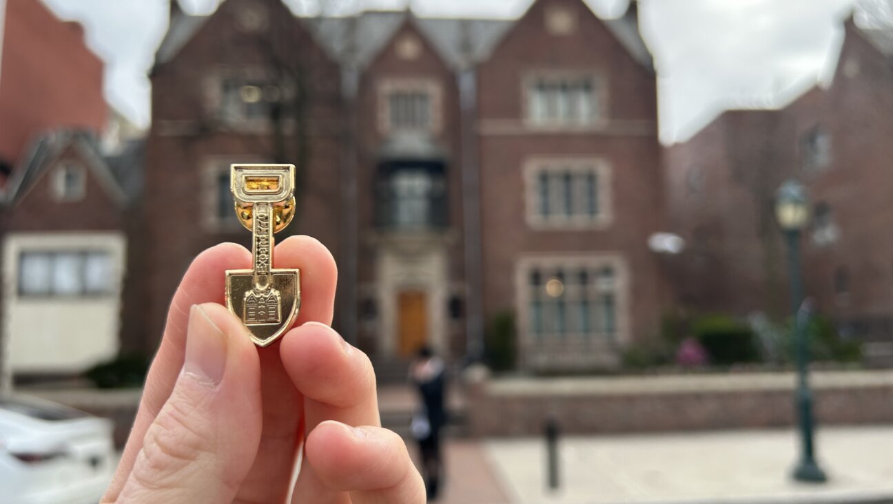 A lapel pin shaped like a shovel with a silhouette of Chabad-Lubavitch headquarters at 770 Eastern Parkway signals support for a tunnel that was dug there illegally. 