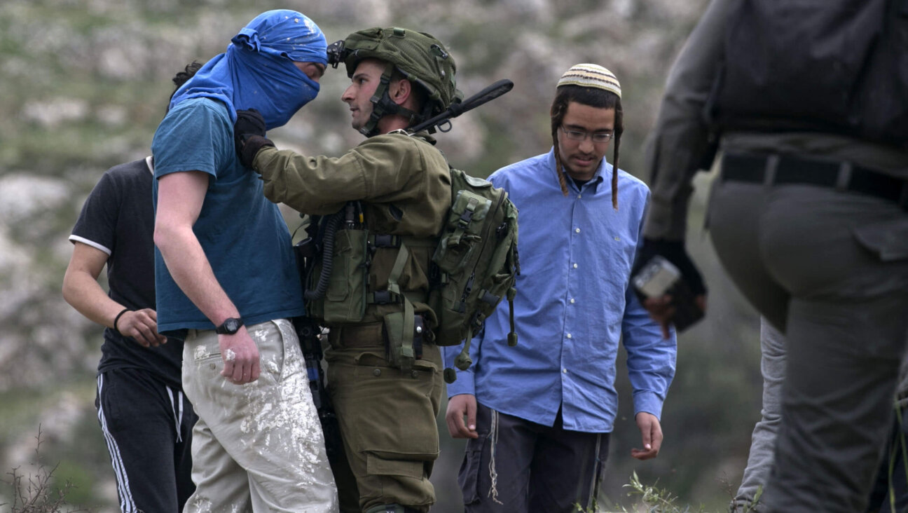 An Israeli soldier scuffles with a masked Israeli settler while trying to remove him from the area of a protest by Palestinians to mark Land Day, in the village of Madama in the Israeli occupied West Bank, March 30, 2017.