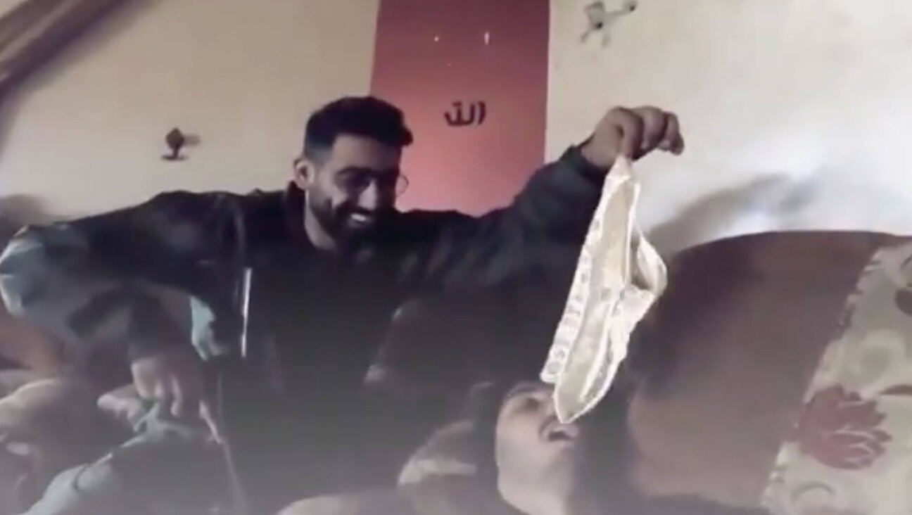 An Israeli soldier with his gun sits and dangles white underwear over the open mouth of another soldier who is lying down beneath him, in a video released on YouTube Jan. 10, said to be filmed in Gaza.