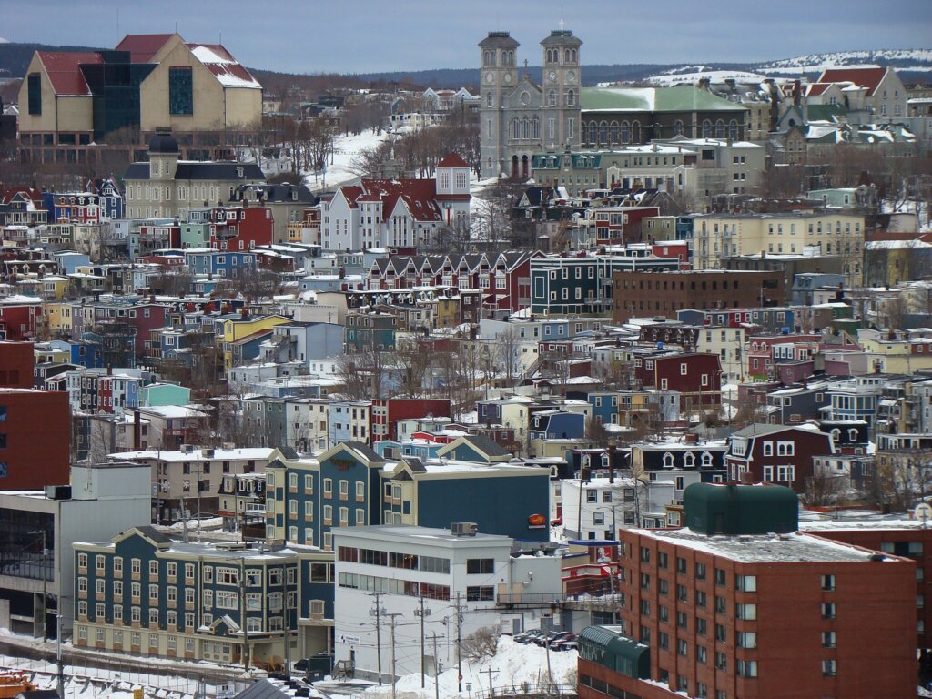 An aerial view of a city full of multi-colored houses covered in snow.