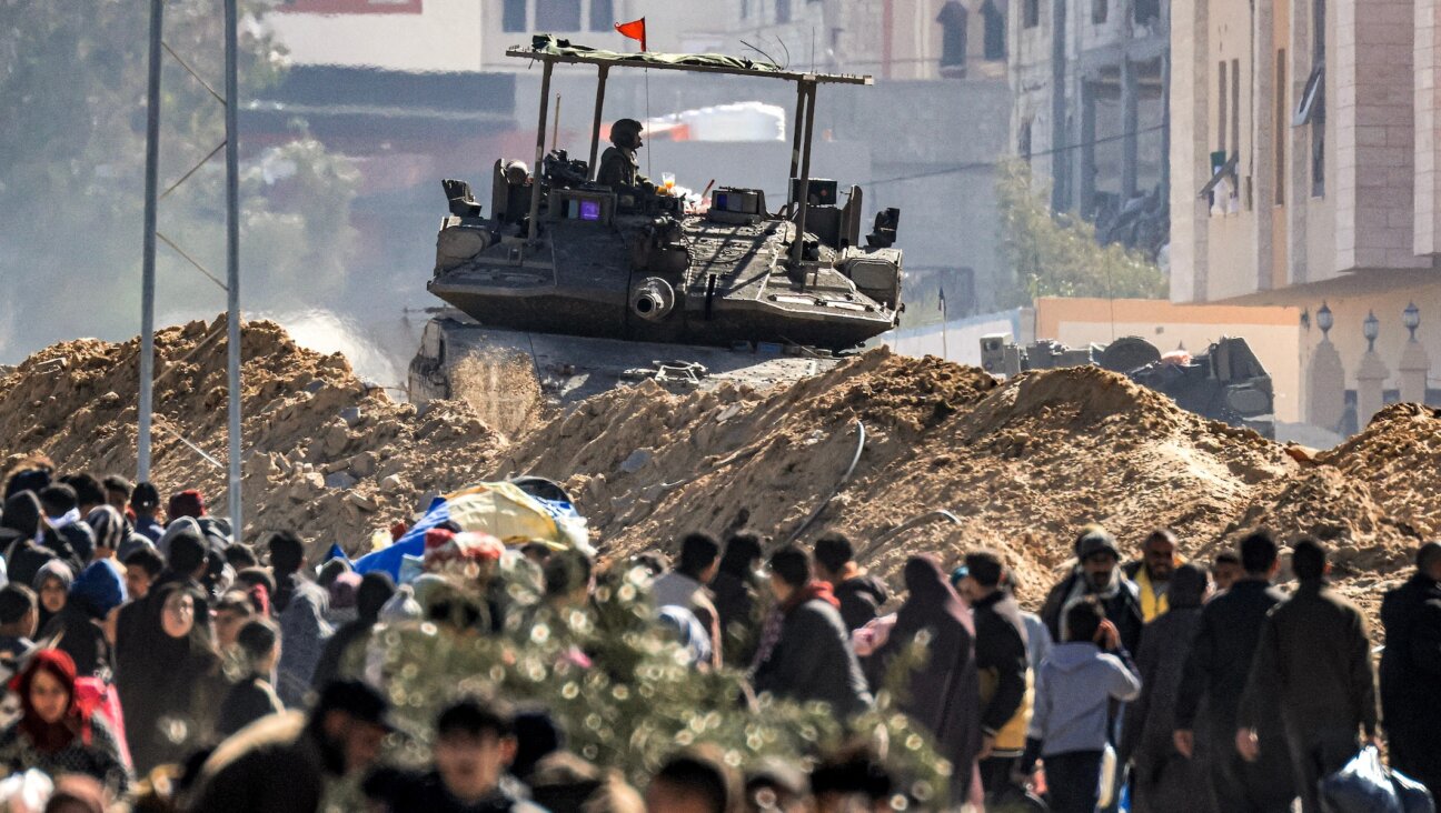 An Israeli battle tank is deployed to guard a position as displaced Palestinians flee from Khan Yunis in the southern Gaza Strip on Jan. 30, 2024. (Mahmud Hams/AFP via Getty Images)