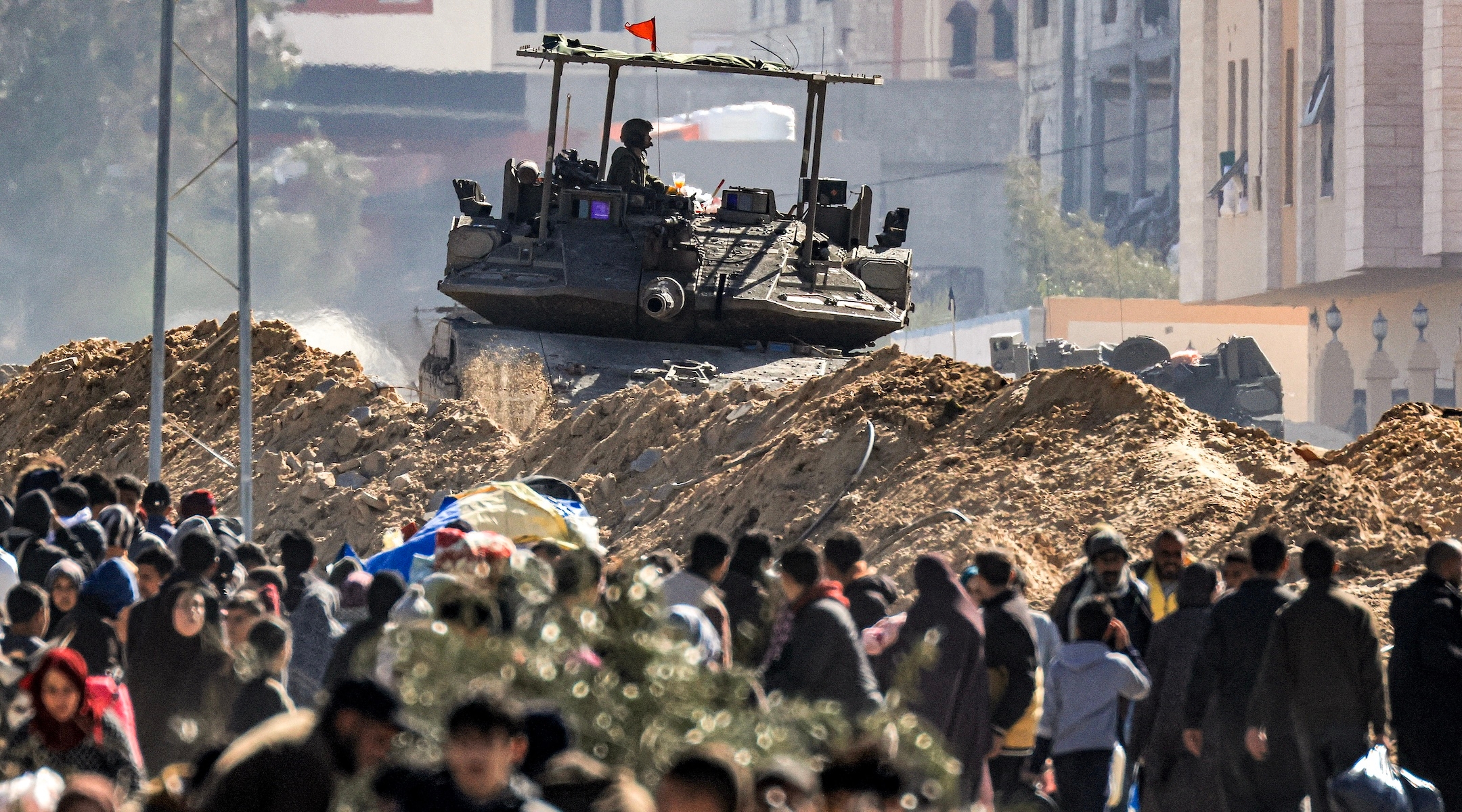 An Israeli battle tank is deployed to guard a position as displaced Palestinians flee from Khan Yunis in the southern Gaza Strip on Jan. 30, 2024. (Mahmud Hams/AFP via Getty Images)