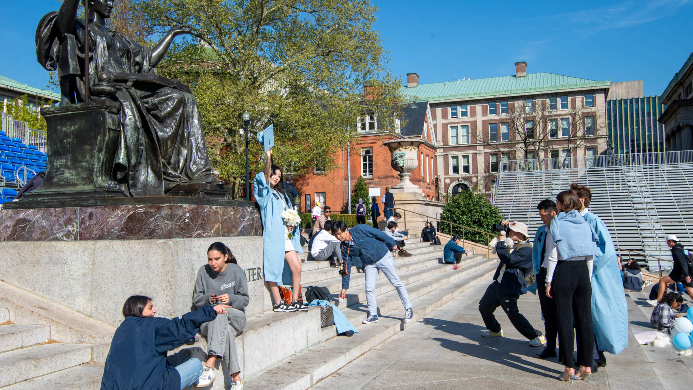 Students in cap and gown pose for photos on the Columbia campus.