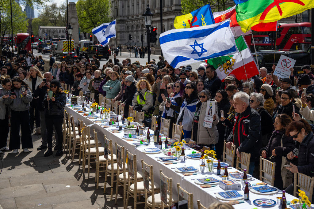 People gather around an empty Passover Seder table featuring 133 chairs for the hostages, opposite Downing Street on April 17, 2024 in London. 